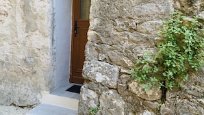 Un arco in pietra conduce a una porta in legno con un vetro.