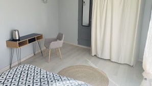 Una camera da letto moderna con un letto, una scrivania, una sedia, uno specchio e una tenda per la doccia.