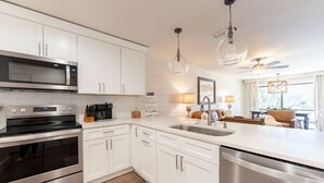 Una cocina moderna con armarios blancos, electrodomésticos de acero inoxidable e iluminación colgante.