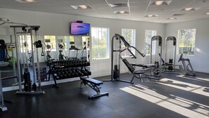A gym with various exercise equipment, large windows, and a TV screen. - Nice designed single family villa facing a lake (Naples)