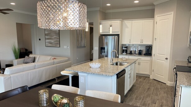 A modern kitchen with white cabinetry, a granite countertop, and stainless steel appliances. - Nice designed single family villa facing a lake (Naples)
