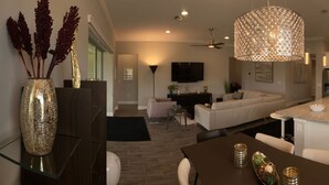 A modern kitchen with a central island, a dining area with a table, and a living area with a sofa and TV. - Nice designed single family villa facing a lake (Naples)