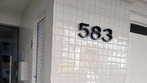 A tiled wall with the number 583, a wooden bench, and a door. - Pé na Areia (RS)