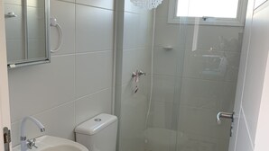 A bathroom with a white sink, toilet, and shower area. - Pé na Areia (RS)