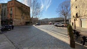 A cobblestone square with buildings, parked cars, and a café with outdoor seating. - La Terrassa del Barri Vell de Girona (Girona)