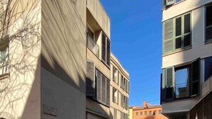 A narrow urban street with buildings featuring balconies and large windows. - La Terrassa del Barri Vell de Girona (Girona)