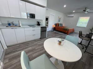 Cozy living space with a round dining table and kitchenette, perfect for a compact home.