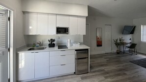 Una cocina moderna con gabinetes blancos, microondas integrado y lavavajillas.