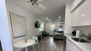 A modern kitchen with white cabinets, a stainless steel sink, and a dining area with a round table and chairs. - 526 · Beautiful and Spacious studio - Casa Habana (Little Habana)