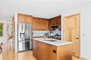 Een moderne keuken met houten kastjes, roestvrijstalen apparatuur en een groot keukenblok met een spoelbak.