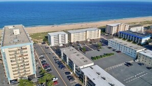 A coastal hotel with multiple buildings, parking lots, and a beach view. - Oceanside 2bed 2bath condo, close to beach & perfect for families! (Ocean City)