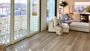 Ein geräumiges Wohnzimmer mit einer großen Schiebeglasdoor zum Balkon, einer modernen Sofagarnitur und einem Essbereich mit Tisch und Stühlen.