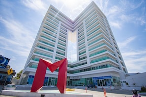 A modern building with a prominent red sculpture in front. - Malecon Location Torre eMe #1501 with Pool (Mazatlan)