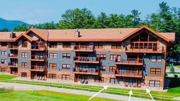 Un chalet à plusieurs étages doté de balcons, d’une façade en pierre et surplombant un paysage montagneux.