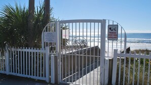 Entrada cerrada con reja a una zona de playa, con letrero que indica propiedad privada y videovigilancia.