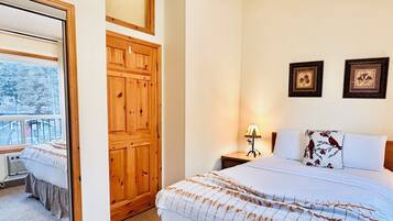 Une chambre à coucher avec un grand lit, une armoire en bois, une table de chevet avec une lampe et deux tableaux encadrés au mur.