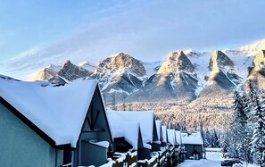 Ein schneebedecktes Dorf mit traditionellen Chalets, einem Berg im Hintergrund und wolkenlosem Himmel.