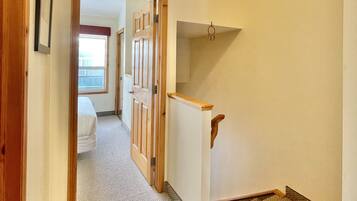 A hallway with a carpeted floor, wooden doors, and a white wall with a picture frame.