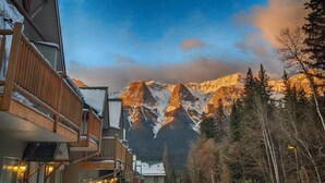 A mountain lodge with a wooden balcony overlooking a snowy mountain range. - Two Storey Cozy Chalet W/2BR&2BA Balcony Mountain Views/By Banff Gate / Sleep 6 (Harvie Heights)