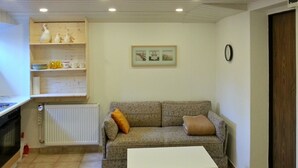 En stue med sofa, sofabord, radiator og et billede i ramme på væggen.