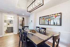 Un coin repas avec une table en bois, des chaises noires et un miroir au mur.