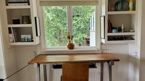 Eine Küche mit Holztisch, einem Stuhl und einem Fenster mit Blick ins Grüne.