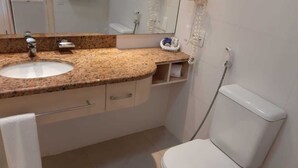 Un bagno con lavabo su piano in granito, un WC bianco e uno specchio sopra il lavabo.