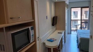 Un angolo cottura compatto con forno a microonde, un tavolino e una sedia.