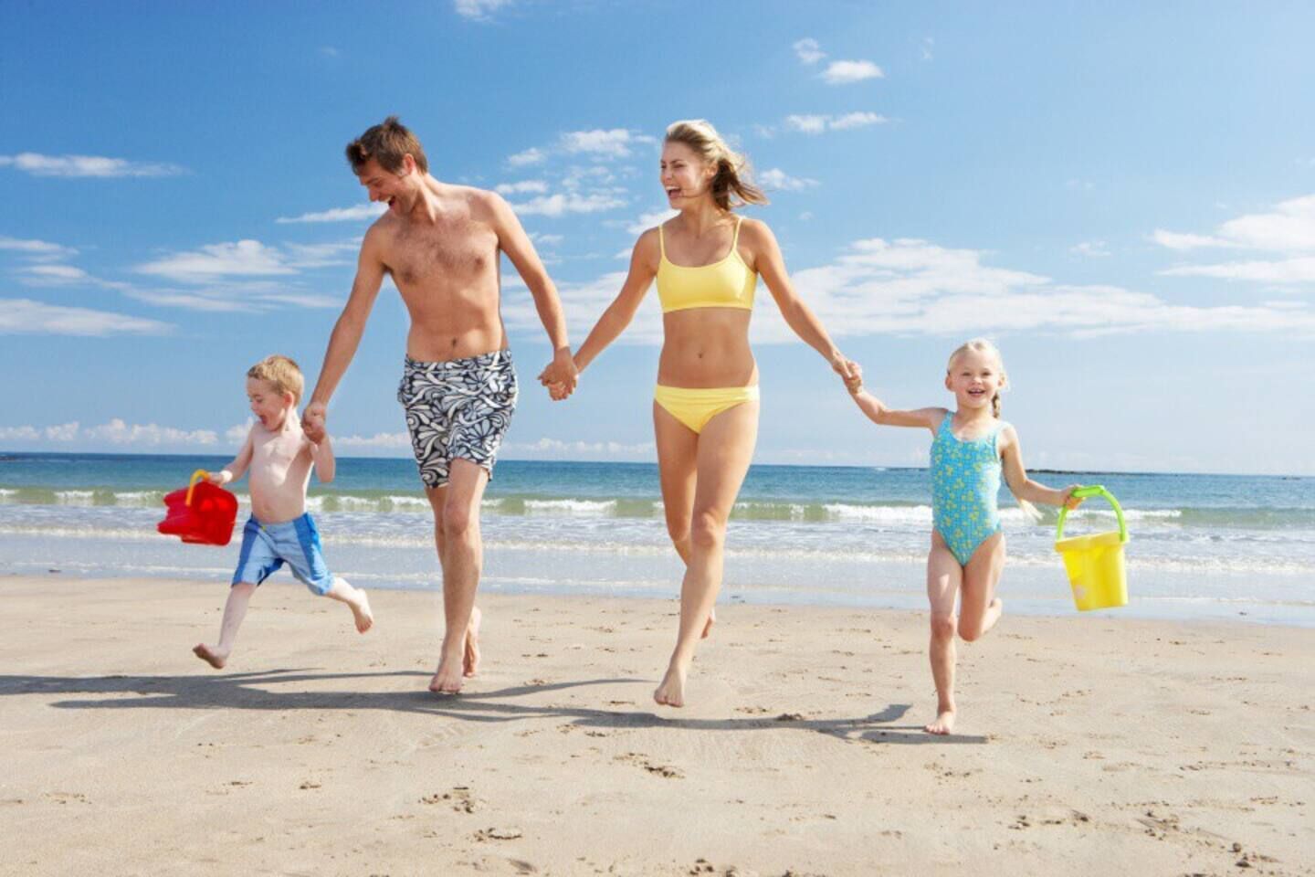 A family walking on a sandy beach with the ocean in the background.