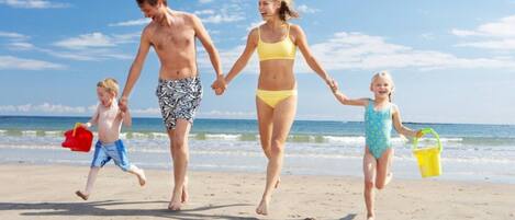 A family walking on a sandy beach with the ocean in the background.