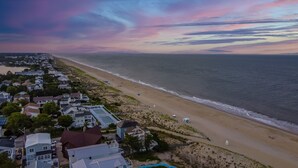 Vista aérea de una zona costera con playa, casas y cielo despejado.