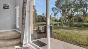 Une pièce dotée d’une grande porte-fenêtre coulissante donnant sur un espace extérieur abrité et équipé d’un appareil de climatisation.