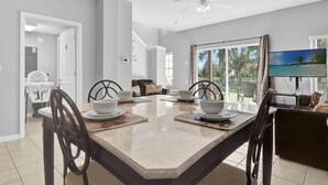 Un espace repas comprenant une grande table, des chaises et un ventilateur de plafond.
