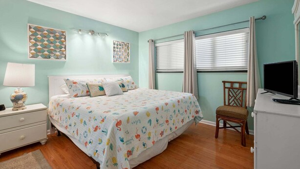 A bedroom with a bed, bedside table, lamp, and a television on a dresser. - Beautiful ocean & beach views, oceanfront condo w/pool, sundeck, family friendly-North Myrtle Beach (North Myrtle Beach)