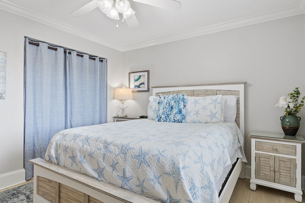 A bedroom with a bed, nightstand, and a ceiling fan.