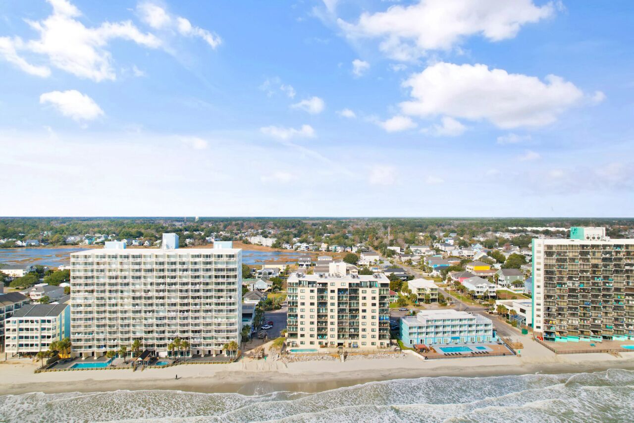 Un hôtel situé sur la côte, composé de plusieurs immeubles de grande hauteur, avec une plage et une vue sur l’océan.