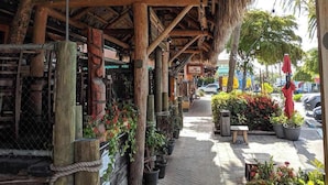 A rustic wooden structure with a thatched roof, potted plants, and a sign for 'The Coroner'. - Siesta Key Village Heated pool (Siesta Key)