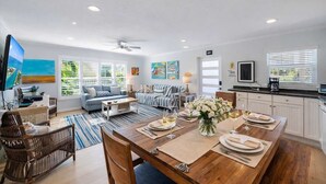 A spacious living area with a dining table set for four, a sofa, a TV, and a kitchen in the background. - Siesta Key Village Heated pool (Siesta Key)