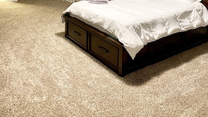 A bedroom with a large bed, two doors, and a ceiling light.