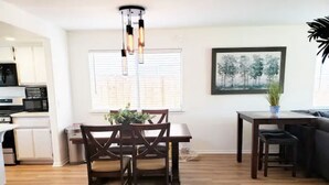 A modern kitchen with white cabinets and a dining area with a wooden table and chairs. - Spacious Whole Residence w/ Bikes--Close to Beach! (Oceano)