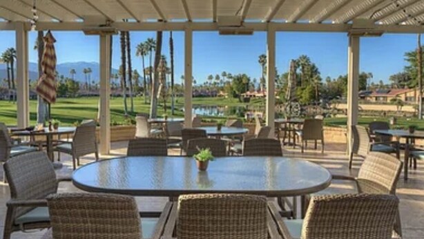 An outdoor patio with a round table and wicker chairs, overlooking a golf course. - Great resort living in Palm Desert (Palm Desert)