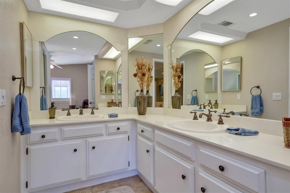 A modern bathroom with two sinks, large mirrors, and a vanity with drawers.