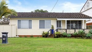 Ein eingeschossiges Haus mit Ziegeldach, einer Veranda und einem kleinen Vorgarten.