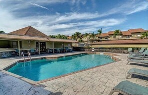 A swimming pool with lounge chairs and a covered seating area. - Cape Coral Costal Escape (Cape Coral)