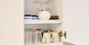 Un armario de cocina con repisas de almacenamiento que contienen varios utensilios de cocina.