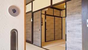 A traditional Japanese room with tatami flooring, sliding doors, and a wooden panel wall.