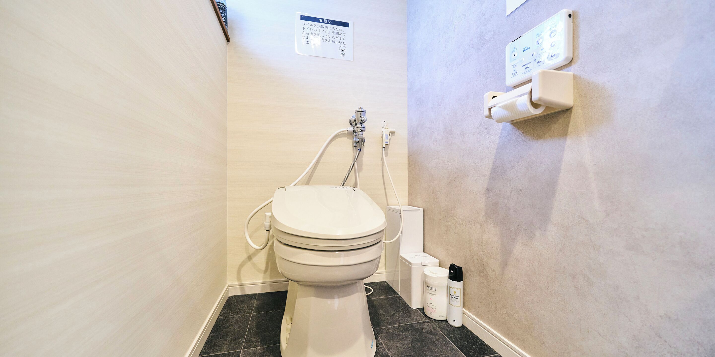 A bathroom with a toilet, a shower, and a wall-mounted electrical outlet.