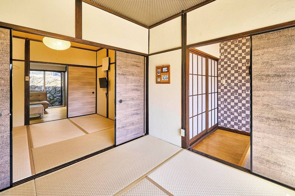 A traditional Japanese room with tatami flooring, sliding doors, and a view of a garden.