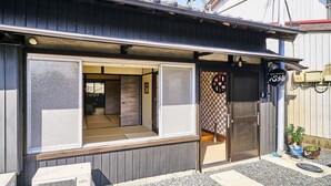 A traditional Japanese house with a sliding door, a small outdoor seating area, and a visible entrance.