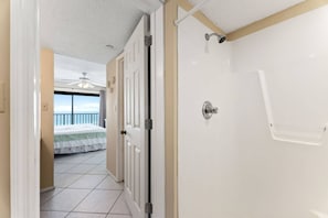 A hotel room with a balcony, a bed, and a shower.